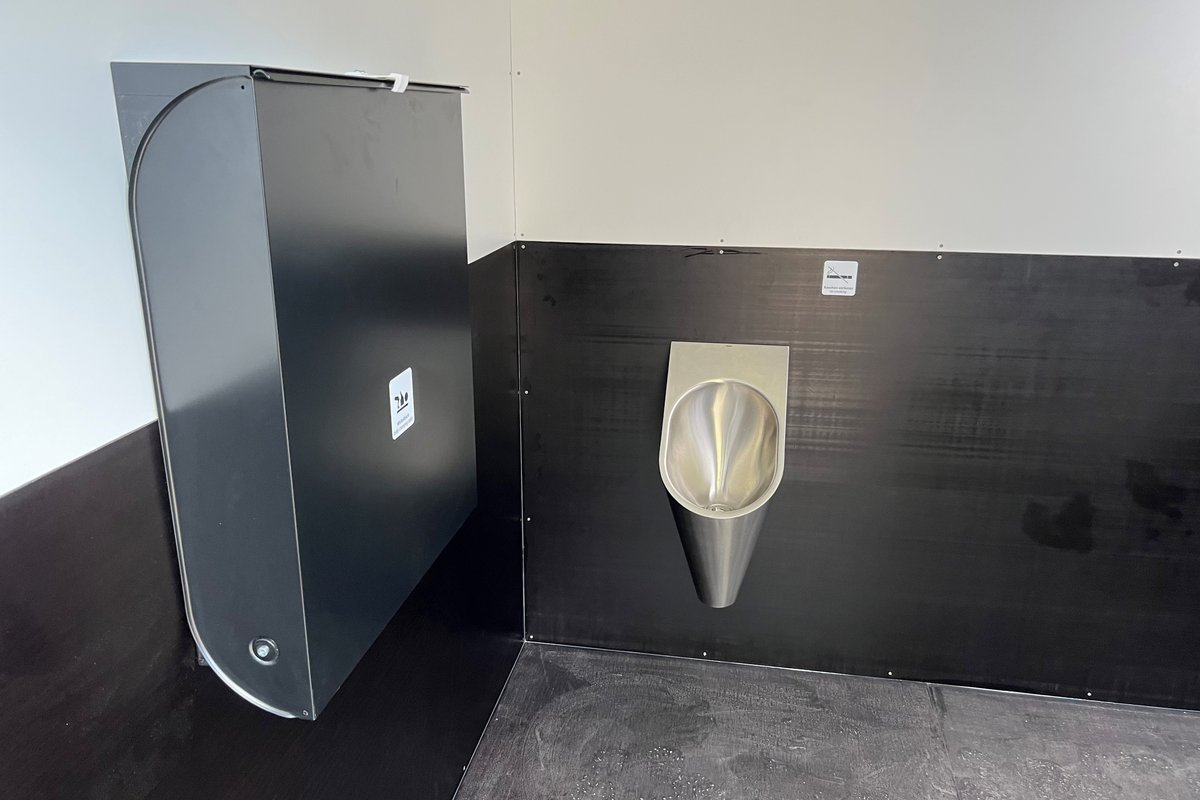 Urinal und Wickeltisch im Innenraum des öffentlichen WCs