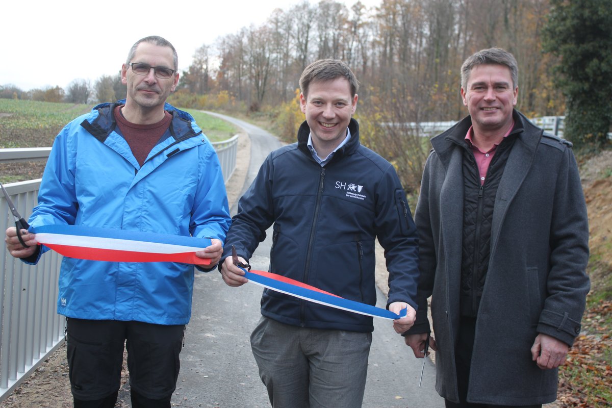 Bürgermeister Robien, Bürgermeister Schöning und Staatssekretär von der Heide durchschneiden das Symbole Band zur Eröffnung des Radweges zwischen Lensahn und Schönwalde
