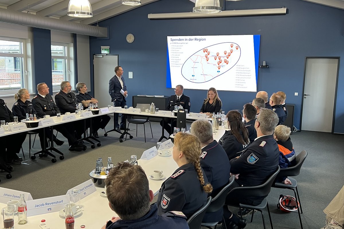 Mehrere Feuerwehrmitglieder sitzen an einem Tisch und verfolgen eine Präsentation