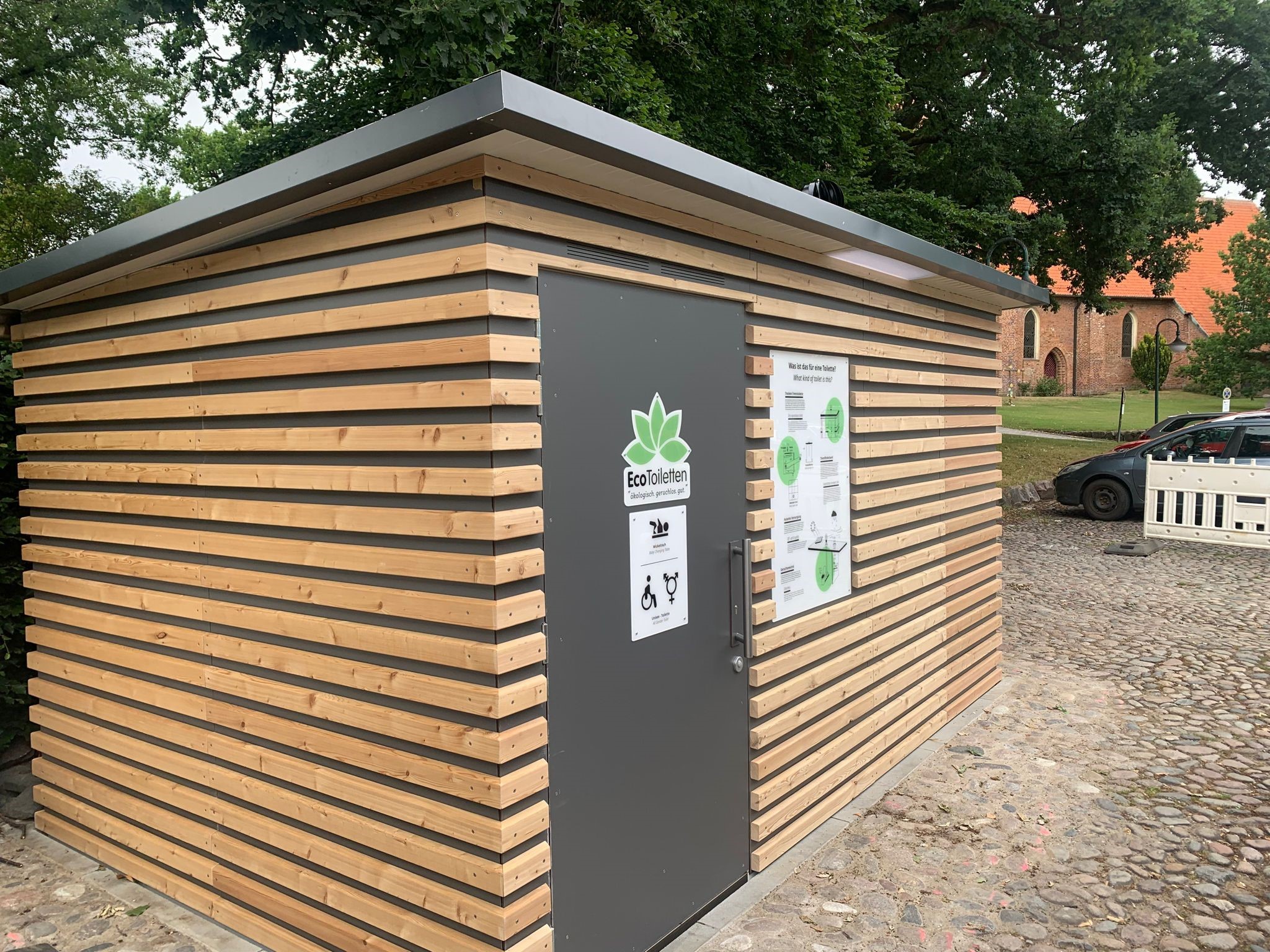 Toilettengebäude mit Holzverkleidung auf dem Kirchplatz Lensahn